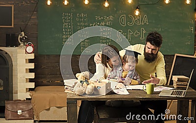 Homeschooling concept. Parents teaches son, chalkboard on background. Boy listening to mom and dad with attention Stock Photo