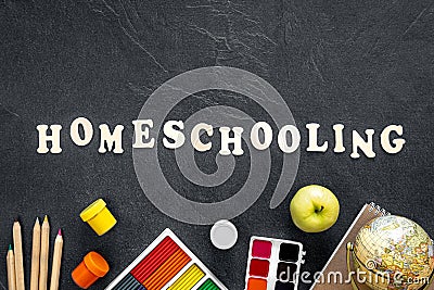Homeschooling word made of wooden letters on a black background, top view. Stock Photo