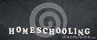 Homeschooling word made of wooden letters on a black background, top view. Stock Photo