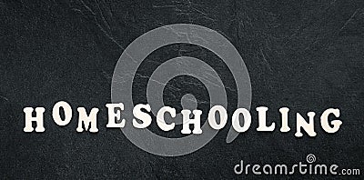 Homeschooling word made of wooden letters on a black background, top view. Stock Photo