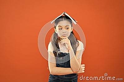 Homework concept. Homeschooling and private lesson. Book on her head. Little girl book roof head. Small girl book orange Stock Photo