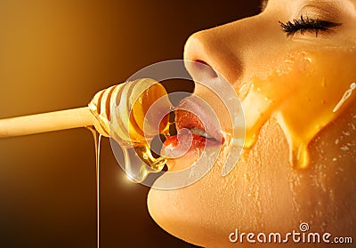 Honey dripping from honey dipper on sexy girl lips. Thick honey dipping from the wooden honey spoon. Beauty model woman Stock Photo