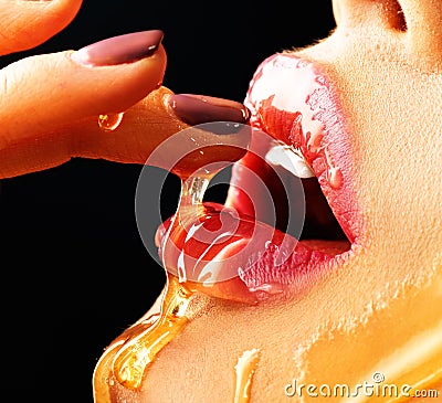 Honey dripping on girl lips. Beauty model woman eating honey Stock Photo