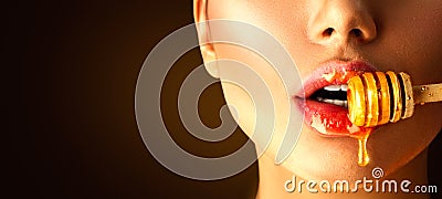 Honey dripping on girl lips from the wooden spoon Stock Photo