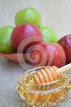 Honey in a glass bowl and colorful apples in the background Stock Photo