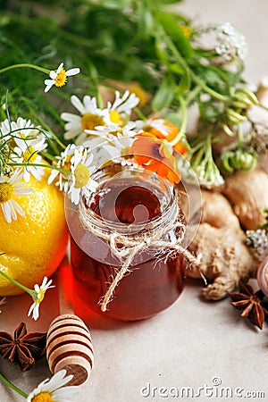 Honey in a glass jar with camomile calendula flowers, ginger root, garlic, anise - immunity tea ingredients, seasonal concept of Stock Photo