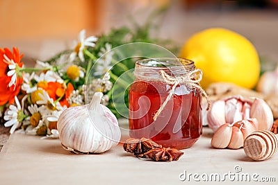 Honey in a glass jar with camomile calendula flowers, ginger root, garlic, anise - immunity tea ingredients, seasonal concept of Stock Photo