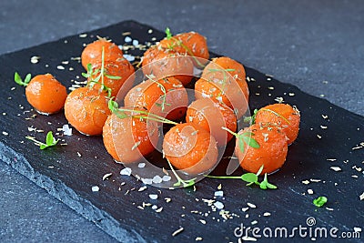 Honey glazed baby carrots with sea salt and thyme on a grey abstract background. Healthy eating concept. Fastening food Stock Photo
