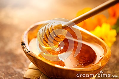 Honey. Healthy organic thick honey dripping from the honey dipper in wooden bowl. Sweet dessert Stock Photo
