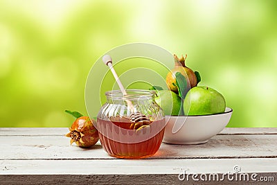 Honey jar and fresh apples with pomegranate over green bokeh background Stock Photo