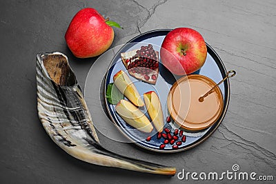 Honey, pomegranate, apples and shofar on black table, flat lay. Rosh Hashana holiday Stock Photo