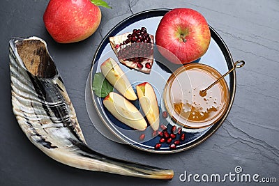 Honey, pomegranate, apples and shofar on black table, flat lay. Rosh Hashana holiday Stock Photo