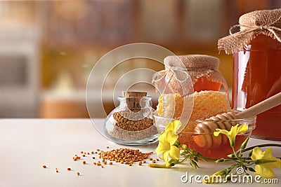 Honey pots honeycomb and bee pollen on white kitchen table Stock Photo