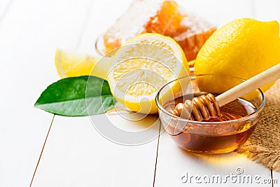 Honeycomb on dish with honey dipper with lemons on white wood background Stock Photo