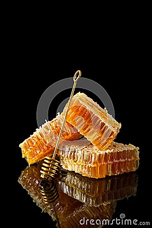 Honeycomb with natural honey and golden dipper on black background with reflection. Side view, close up. Natural, organic food. Stock Photo