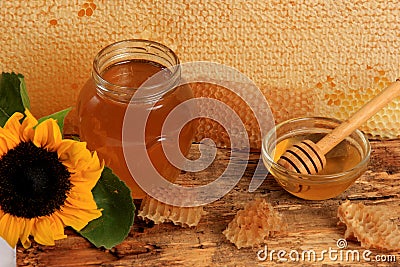 Honeycomb in a wooden frame decorated with sunflower and glass jar of honey on a wooden background Stock Photo