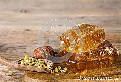 Honeycombs and honey spoon and dried chamomile flowers Stock Photo