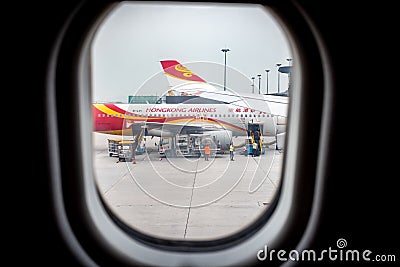 HONG KONG, CHINA - JANUARY 14, 2019: Window view airplane, Hong Kong airlineâ€™s airplane preparing to leave and loading luggage Editorial Stock Photo