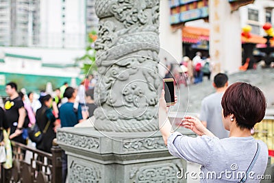 HONGKONG, China - APRIL 2018: occasional female visitor of wong tai sin temple in Hong Kong taking picture of stone dragon Editorial Stock Photo