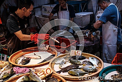 HongKong, China - November, 2019: Vendor preparing fish on food market in HongKong, China Editorial Stock Photo