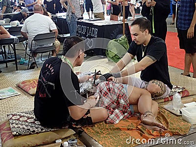 Lady lays on floor as she gets tattoo Editorial Stock Photo