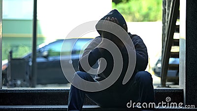 Hooded black male teenager closing face with hands, depression problem Stock Photo