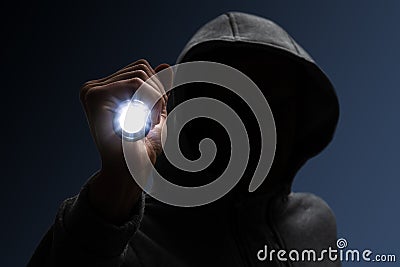 Hooded burglar. Silhouette of thief and flashlight Stock Photo