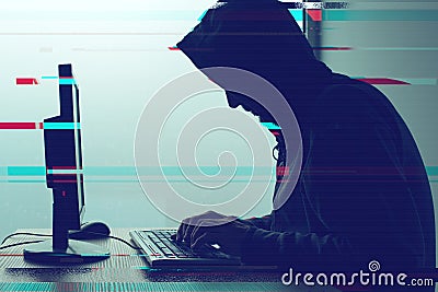 Hooded computer hacker working on desktop PC computer Stock Photo