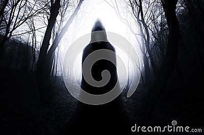 Hooded ghost in haunted forest with fog on Halloween night Stock Photo