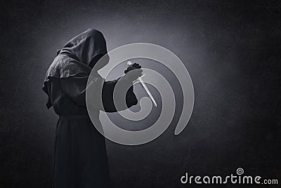 Hooded man with dagger in the dark Stock Photo