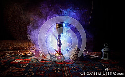 Hookah hot coals on shisha bowl making clouds of steam at Arabian interior. Oriental ornament on the carpet eastern tea ceremony. Stock Photo