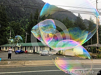 A man blowing huge bubbles along the side of the road, trying to sell bubble makers to people passing by Editorial Stock Photo