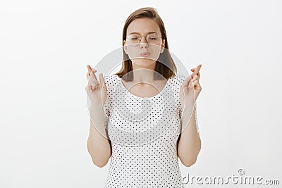 Hope god hear prayers. Studio shot of intense determined good-looking female in glasses, closing eyes and crossing Stock Photo