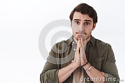 Hopeful clingy guy say please. Cute handsome man making innocent desperate face as press hands together in pray, pursing Stock Photo