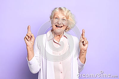 Hopeful happy kind old woman crossing fingers hoping for good luck Stock Photo