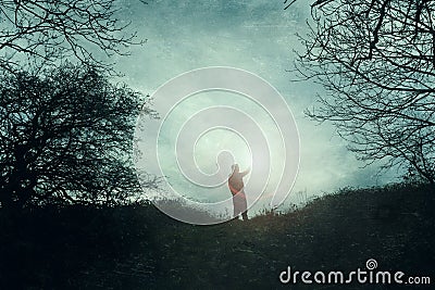 A hopeful but mysterious concept of a man holding up a glowing light to the sky. On a moody winters day in the countryside. With Stock Photo