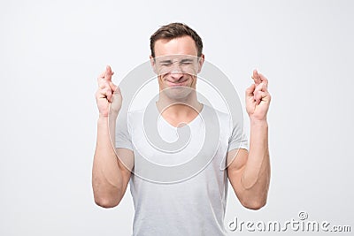 Hopeful young italian male crosses fingers before having job interview, worries much Stock Photo