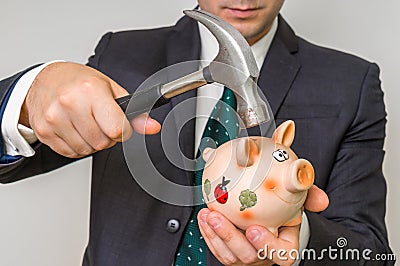 Hopeless businessman breaking piggy bank with hammer Stock Photo