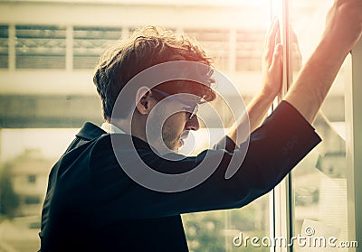 Hopeless Businessman looking out windows with worrying face standing Stock Photo