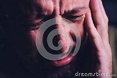 Hopelessness and despair, closeup of portrait of sad crying adult man grieving in dark room Stock Photo