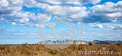 View of Young Nicks Head with beachside golden summer dry dune grasses and blue sky with cumulus clouds, Gisborne, New Zealand Stock Photo