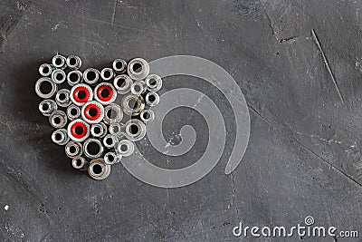 Heart made of pop rivet nuts and locknuts with red plastic, stainless steel mandrel on black tectured chalk board Stock Photo