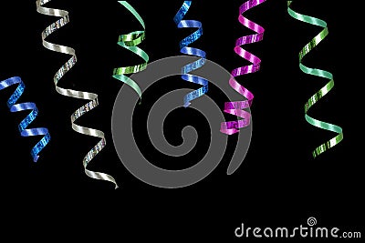 Horizontal image with close-up multi coloured rolls curly ribons hanging from the top on black bacgroung Stock Photo