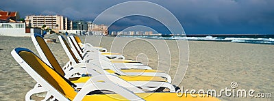 Horizontal image cropped view yellow blue color empty sunbeds deck-chairs in a row on the sandy beach, La Manga del Mar Menor Stock Photo