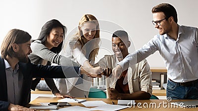 Five multiracial staff members show unity stacked hands in circle Stock Photo