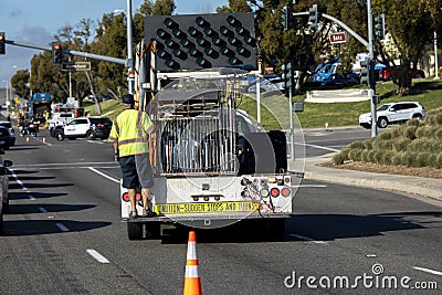 Horizontal image of Worker behind utility truck placing bright orange traffic cones on roadway Editorial Stock Photo