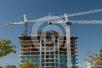 Horizontal mage of White crane towers at a large construction site for a condominium complex Stock Photo