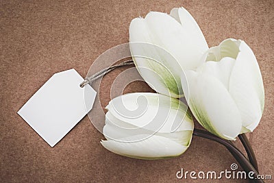 Artificial white tulips with greeting card in kraft paper background. Concept for Mother`s Day with copy space. Stock Photo