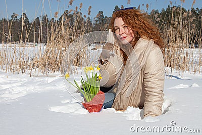 Charismatic pretty woman sitting in snowdrift and holding her coat collar Stock Photo