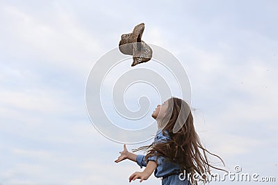 Horizontal photo of a running girl who throws up her hat Stock Photo